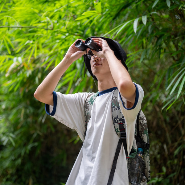 Person using binoculars in a forest setting