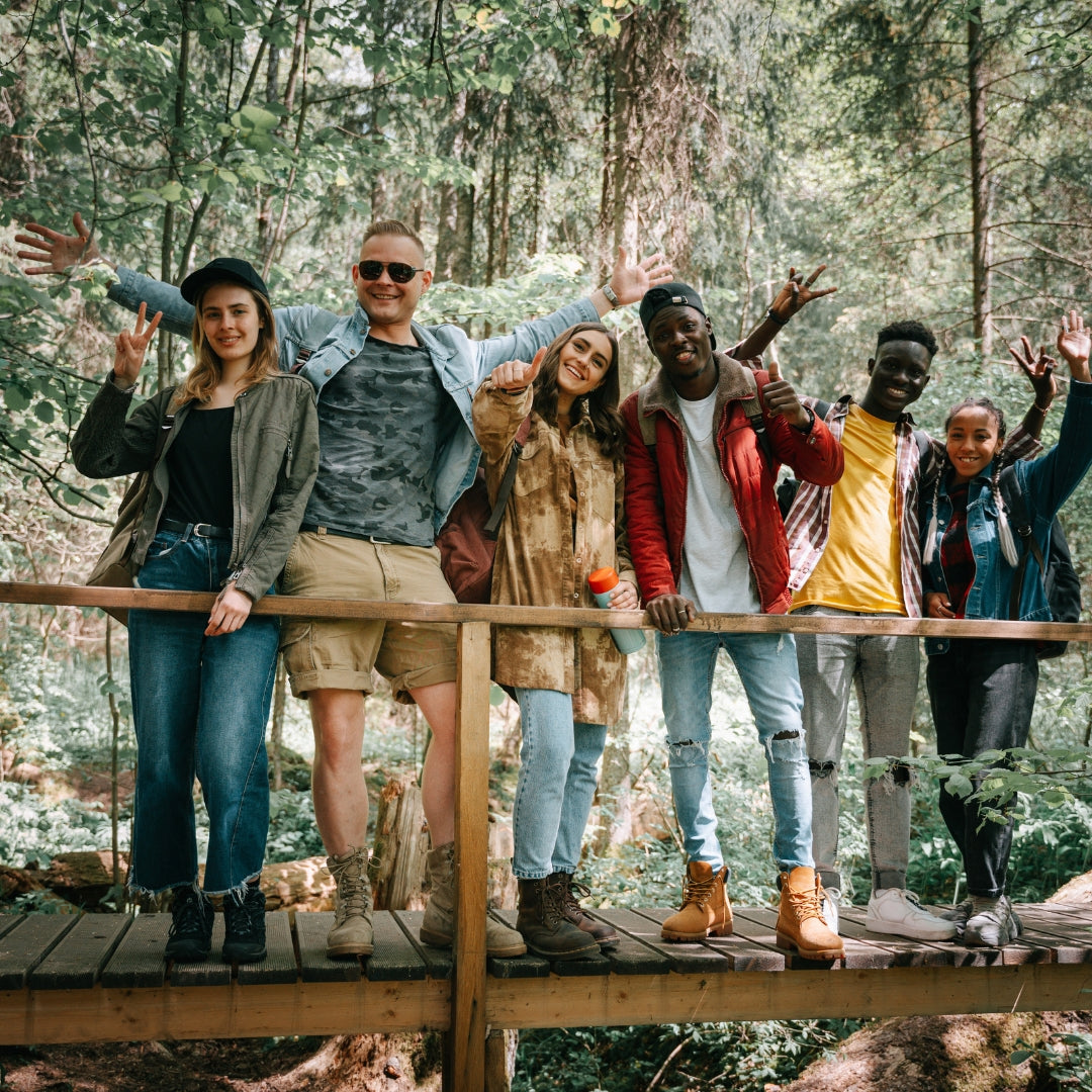 Group of people standing on a wooden bridge in a forest