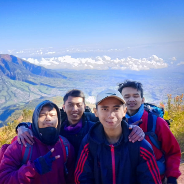 Four friends posing for a photo with a scenic mountain view in the background