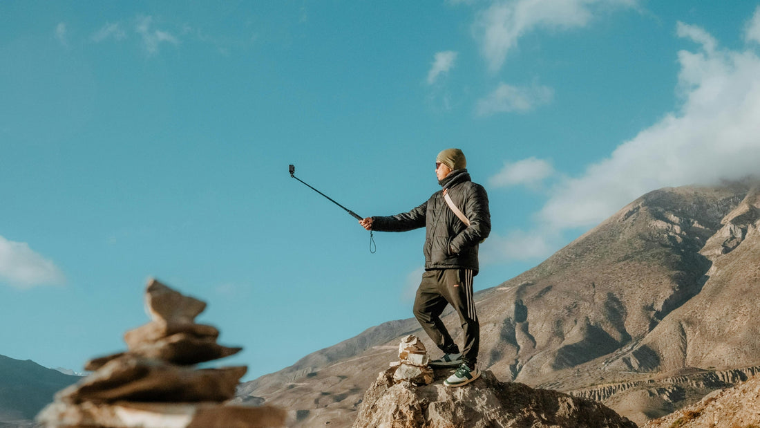 Adventurer taking selfie on rocky mountain peak with scenic valley views