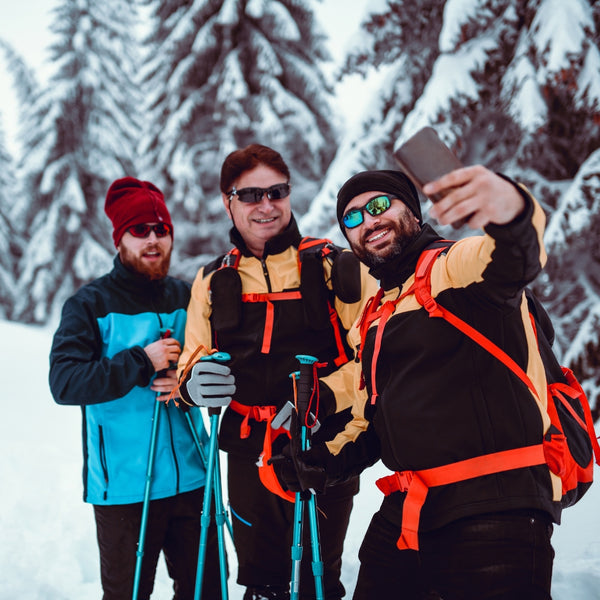 Three skiers taking a selfie in a snowy forest