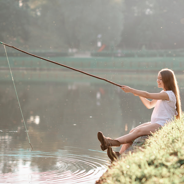 Woman fishing by a lake with a blurred background